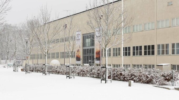 marken och trädtoppar tunga av snö och i skymningen ser man tekniska museets entré.