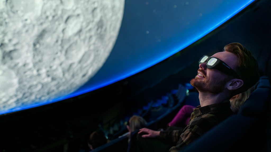 Man sitting in a chair with VR-glasses in a dome.
