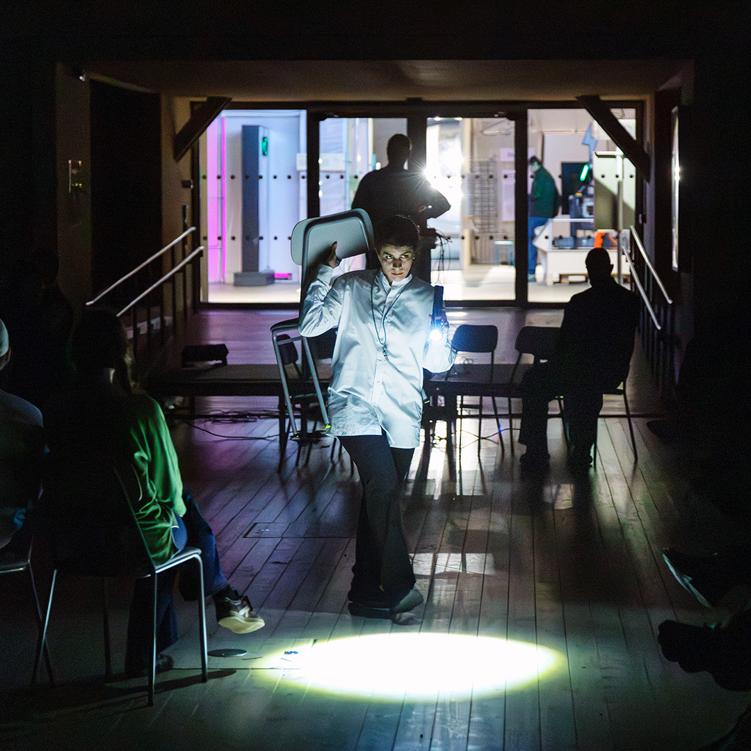 Kvinna klädd i itp och håller i ljus som kör ett performance.