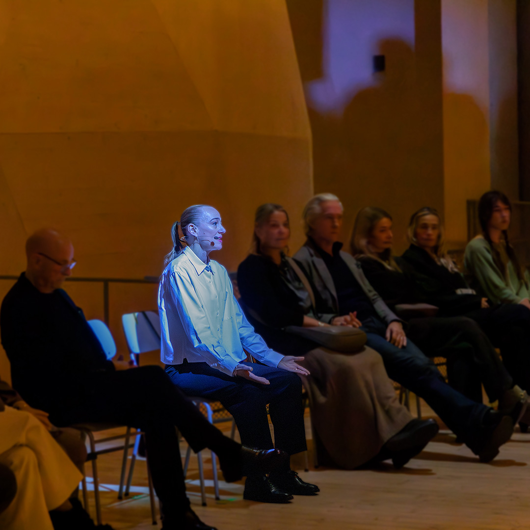 Kvinna med strålkastarljus som sitter ned bland publiken.