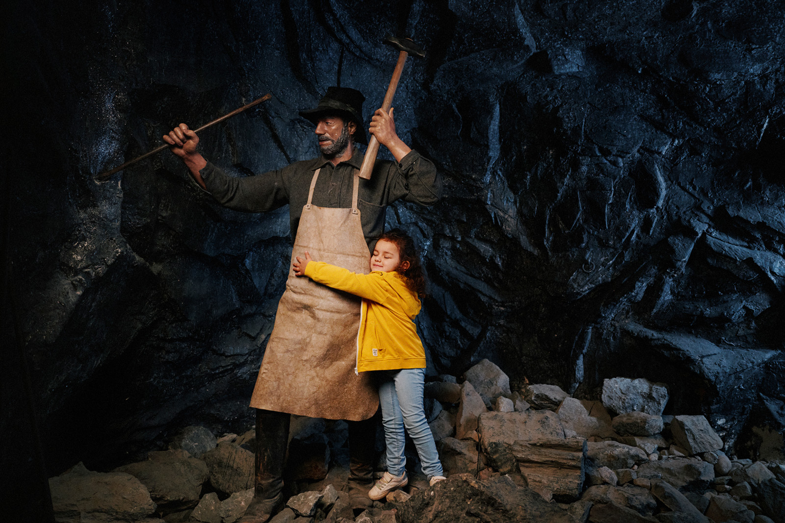 litet barn kramar om en vaxdocka som föreställer en gruvarbetare