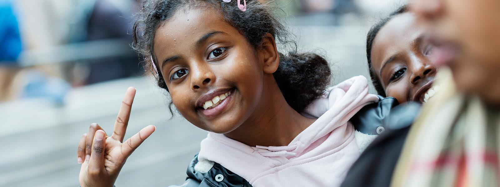 Glad tjej som gör ett peacetecken och ler mot kameran