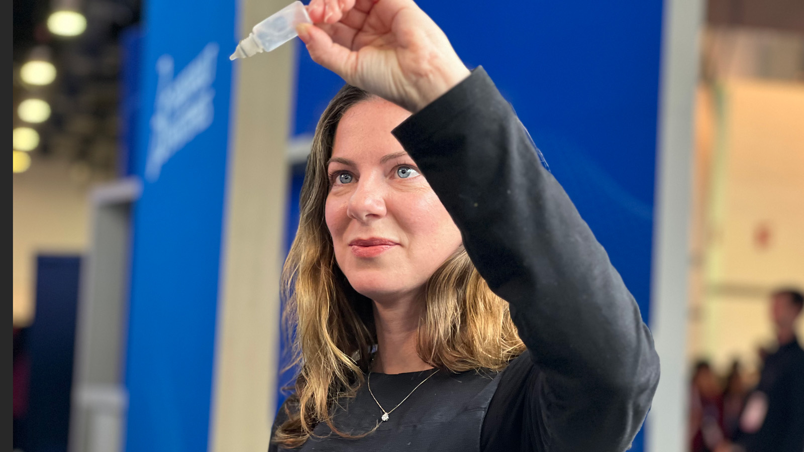 kvinna som håller upp ögondroppar och tittar intensivt