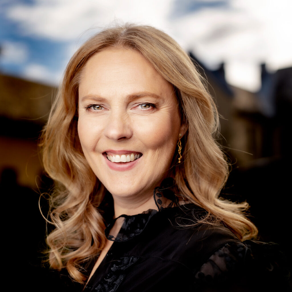 Porträttbild på kvinna med blont hår och stort leende.